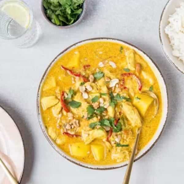 Yellow Thai curry with chicken, potatoes, red peppers, peanuts, and cilantro, served with rice.