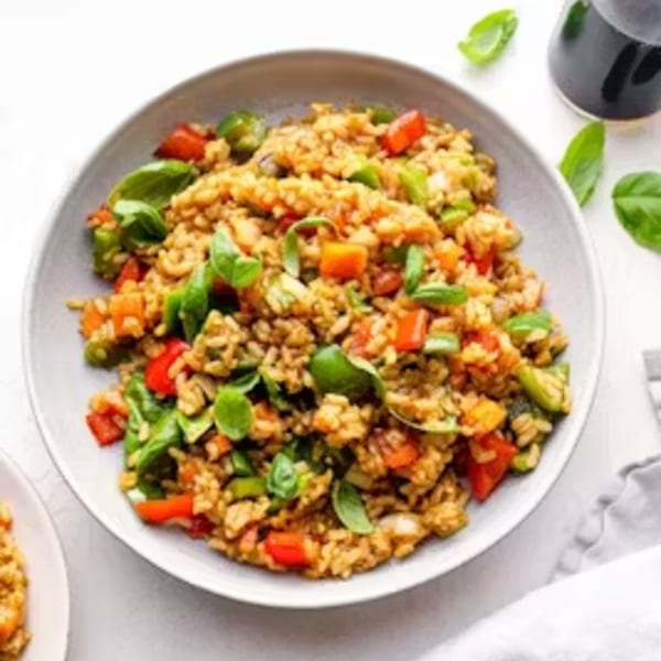 A bowl of Thai fried rice with bell peppers, basil, and other vegetables.