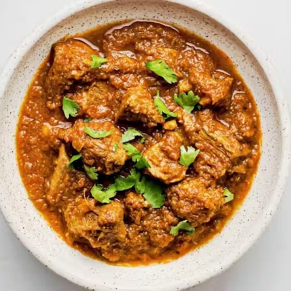 Close-up of a bowl of Royal Taw Win Thai & Burmese Restaurant's rich, savory curry with cilantro garnish.